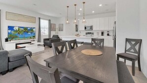 A modern living room with a dining area, white cabinetry, and a flat-screen TV. - 3 Beds 3 Baths Cozy Town Home 3 Bedroom Townhouse (Davenport)
