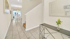 A modern interior with a staircase, a glass console table, and a framed picture on the wall. - Beautiful Paradise Palms Retreat 4 Bedroom Townhouse (Kissimmee)