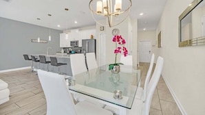 A modern kitchen with white cabinets, a stainless steel refrigerator, and a microwave. - Beautiful Paradise Palms Retreat 4 Bedroom Townhouse (Kissimmee)