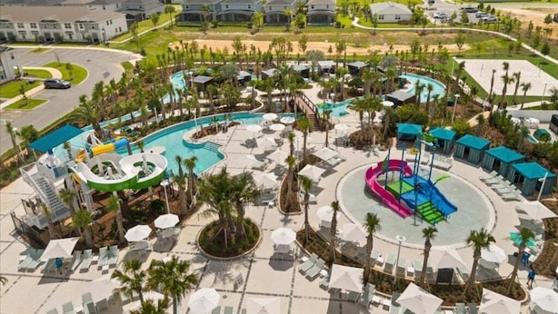 Ein Resort mit zentral gelegener Poolanlage, mehreren Wasserrutschen und einer umliegenden Pool-Lounge mit Sonnenschirmen.