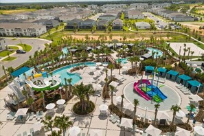 A resort with a central pool area, multiple water slides, and a surrounding poolside lounge area with umbrellas. - Mickey's Movie Mogul Theme Fun House! 7 Bedroom Villa (Clermont)