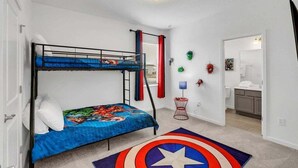 A room with a bunk bed, a small side table, a decorative rug, and a door leading to a bathroom. - Everyone Can Come So Much Space Pool Home! 15 Bedroom Villa (Kissimmee)