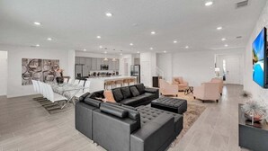 A spacious living area with a sectional sofa, a dining table with chairs, and a kitchen in the background. - Everyone Can Come So Much Space Pool Home! 15 Bedroom Villa (Kissimmee)
