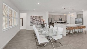 A modern kitchen with white cabinets, a central island, and pendant lighting. - Everyone Can Come So Much Space Pool Home! 15 Bedroom Villa (Kissimmee)