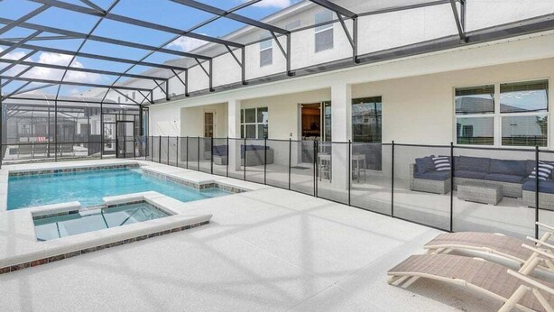 A covered outdoor swimming pool area with lounge chairs and a glass-enclosed patio. - Everyone Can Come So Much Space Pool Home! 15 Bedroom Villa (Kissimmee)