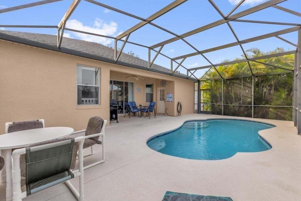 Un espace piscine extérieur abrité, avec une table et des chaises, un patio couvert et une vue sur la verdure environnante.
