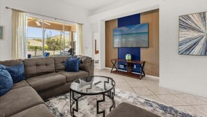 A modern living room with a sectional sofa, a glass coffee table, and a flat-screen TV mounted on a wooden panel wall. - 4 Bed Luxury Quiet & Private Home! 4 Bedroom Villa (Davenport)