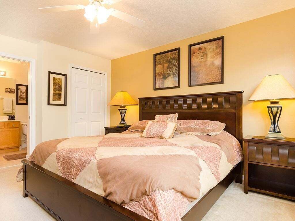 A bedroom with a large bed, two bedside lamps, and framed artwork on the wall.