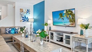 Een moderne woonkamer met een grote flatscreen televisie, een houten salontafel, een bank en een kast met tv-meubel.