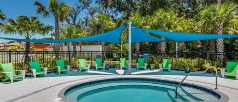 A pool area with a circular pool, green lounge chairs, and a blue canopy.