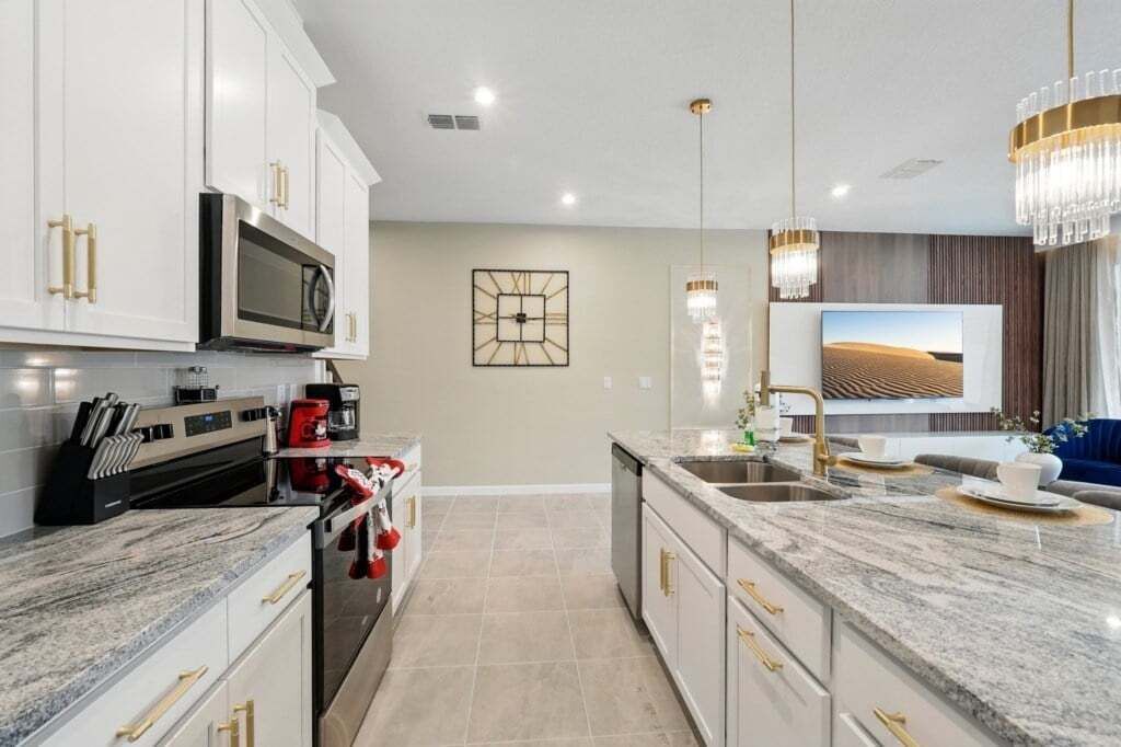 A modern kitchen with granite countertops, stainless steel appliances, and gold handles.
