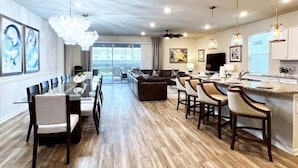 A spacious kitchen with a dining area, wooden flooring, and pendant lighting. - Scifi Theater Amazing Theme 7 Bed Pool Home 7 Bedroom Home (Davenport)
