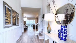 A hallway with a wooden floor, a staircase, and a table with a vase and a lamp. - Scifi Theater Amazing Theme 7 Bed Pool Home 7 Bedroom Home (Davenport)