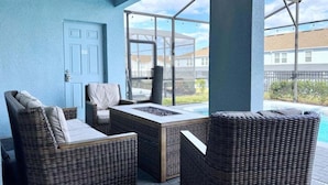 A covered patio area with wicker furniture and a view of a swimming pool. - Scifi Theater Amazing Theme 7 Bed Pool Home 7 Bedroom Home (Davenport)
