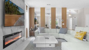 A modern living room with a fireplace, a white sofa, and a coffee table. - Star Wars & More Large Private Pool Lanai Home! 6 Bedroom Villa (Davenport)