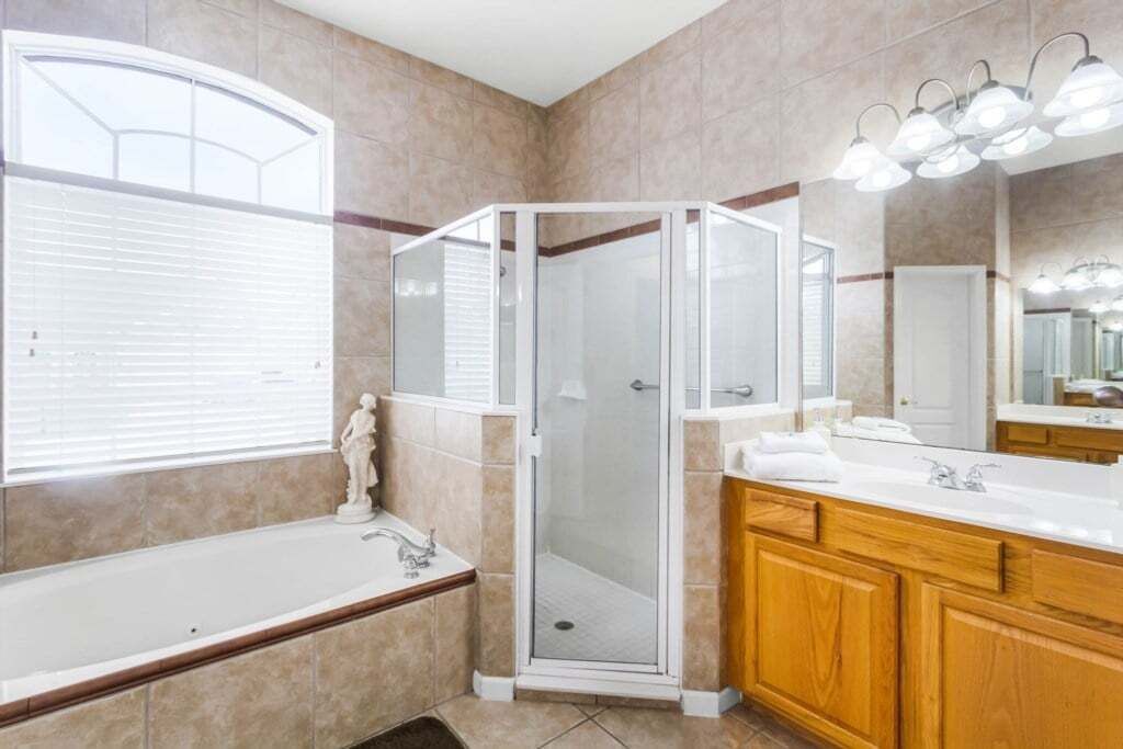 A modern bathroom with a glass-enclosed shower, a bathtub, and wooden cabinetry.