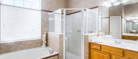 A modern bathroom with a glass-enclosed shower, a bathtub, and wooden cabinetry.