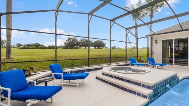 A covered outdoor area with a pool, blue lounge chairs, and a hot tub. - 4 Bed Pool Home, Pool Table & More 4 Bedroom Villa (Davenport)