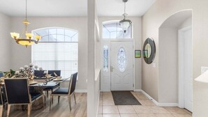 A dining area with a chandelier, a dining table with chairs, and a window with blinds. - 4 Bed Pool Home, Pool Table & More 4 Bedroom Villa (Davenport)