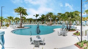 Un espace piscine agrémenté de chaises longues et de parasols, entouré de palmiers.