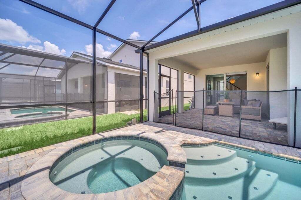 Ein moderner Poolbereich im Freien mit Glasveranda, Whirlpool und Terrasse mit Gartenmöbeln.