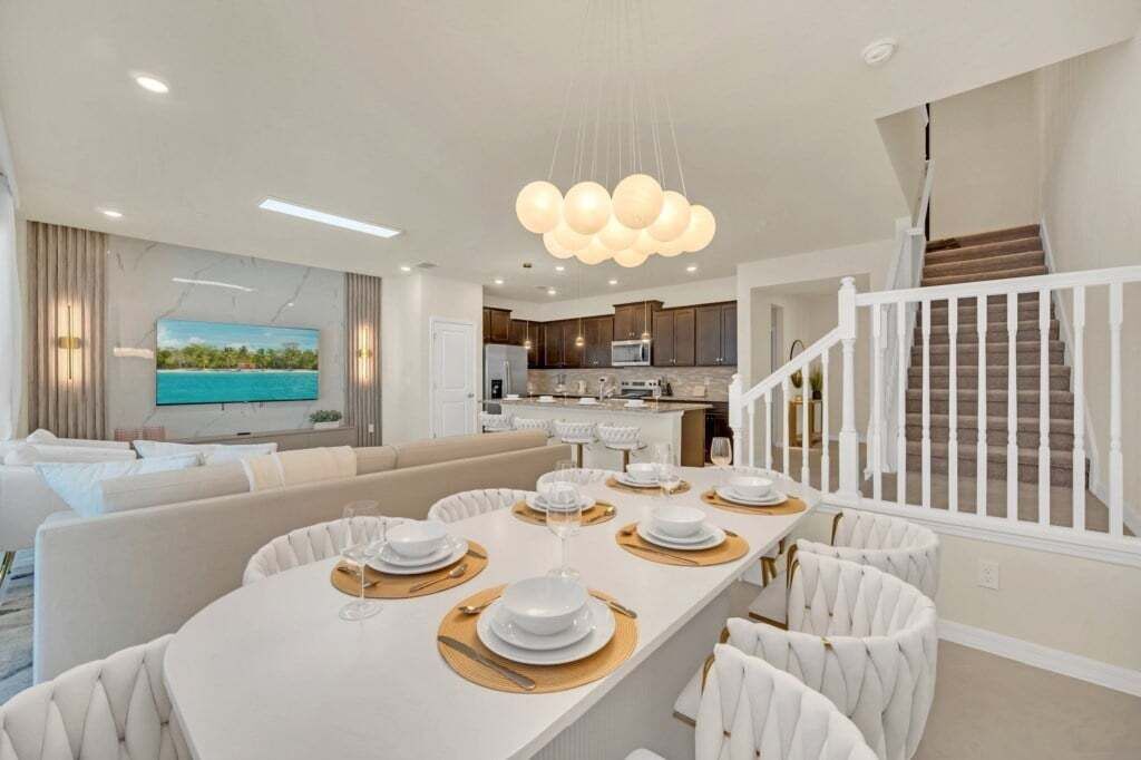 A modern living room with a dining area, a kitchen, and a staircase.