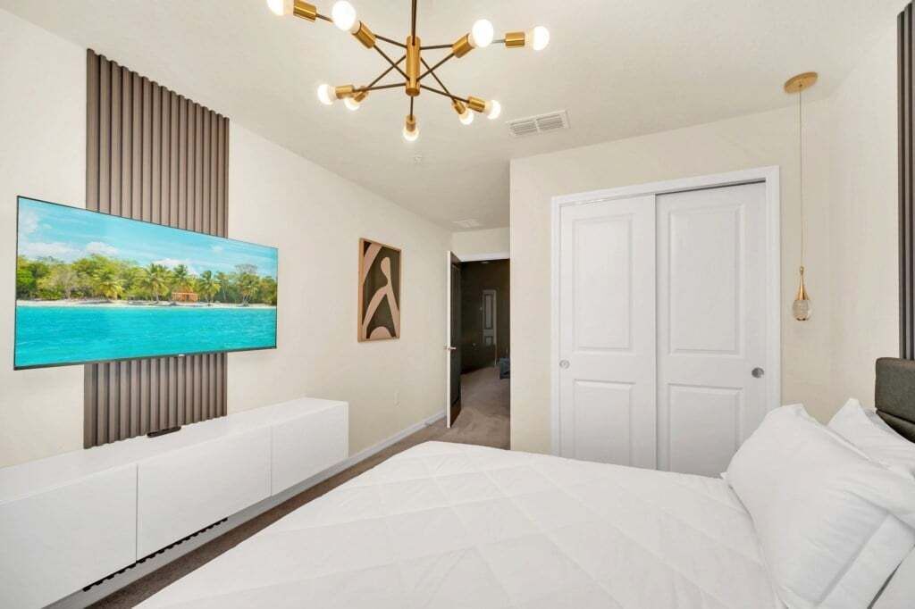 Una camera da letto moderna con un letto grande, una TV montata a parete e un originale lampadario.