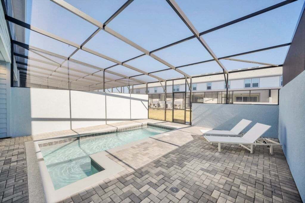 Un espace extérieur abrité avec une piscine, des chaises longues et une vue dégagée sur les bâtiments environnants.