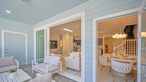 A modern interior with a dining area, a living room with a sofa and chairs, and a kitchen visible through an open doorway. - Luxury Home With Splash Pool 5 Bed Townhome! 5 Bedroom Townhouse (Clermont)