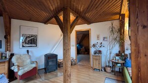 A wooden interior with a fireplace, a chair, a table, and a door leading to another room.