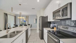 Una cucina moderna con elettrodomestici in acciaio inossidabile, un lavello doppio e una grande isola.