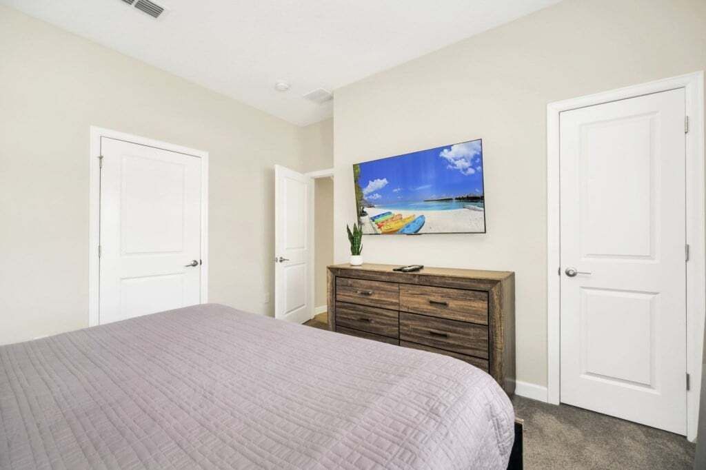A bedroom with a bed, a dresser, and a door.