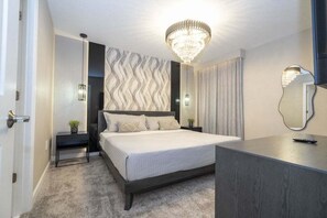 A modern bedroom with a bed, bedside tables, a chandelier, and a mirror. - The Most Stunning Home With Everything You Want! 8 Bedroom Villa (Davenport)