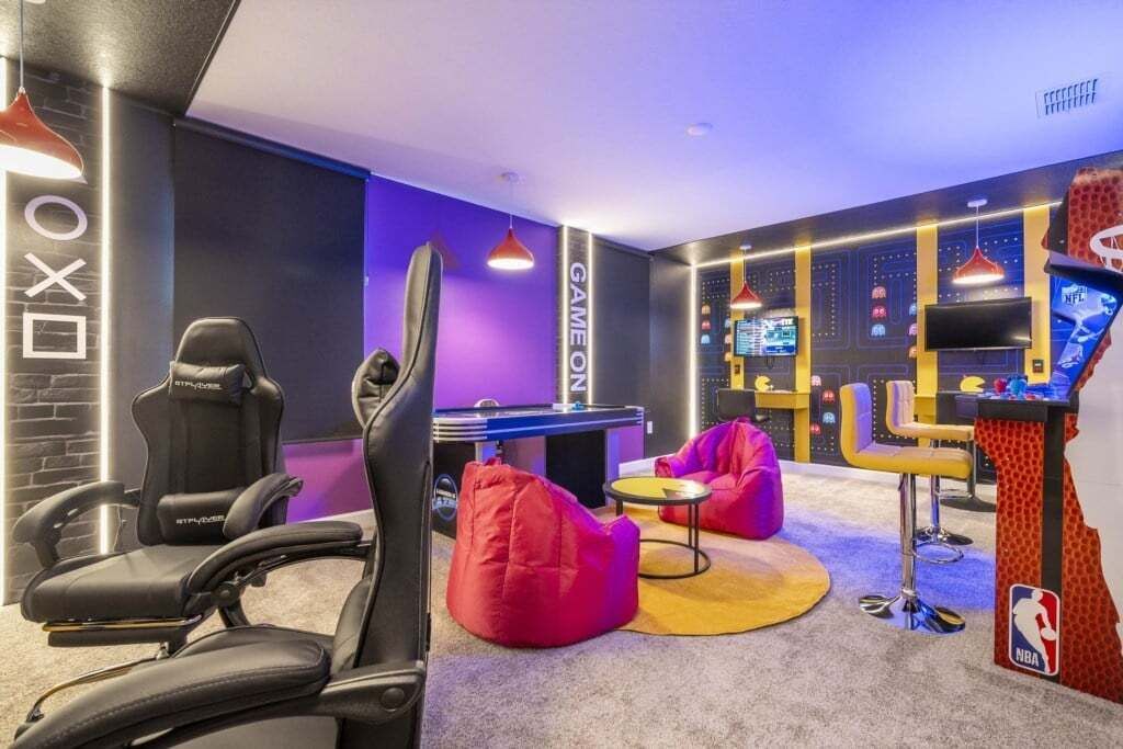 A gaming room with a racing game setup, bean bag chairs, and a pool table.