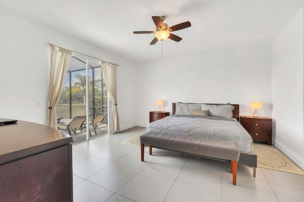 A bedroom with a bed, bedside tables, a desk, and a ceiling fan.