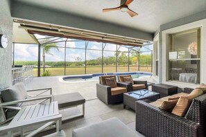 An outdoor patio area with wicker furniture, a ceiling fan, and a view of a swimming pool and greenery. - Beautiful Golf Resort & Private Pool Area! 5 Bedroom Villa (Davenport)