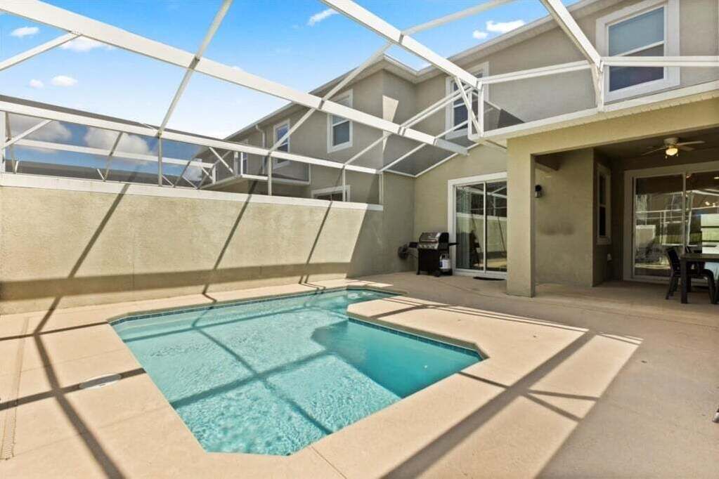 A swimming pool with a glass ceiling, surrounded by a building with a beige exterior and large windows.
