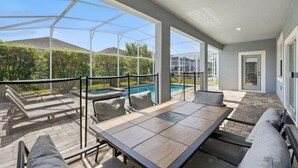 Eine überdachte Terrasse mit Pool, Sitzgelegenheiten im Freien und Blick auf die Umgebung.
