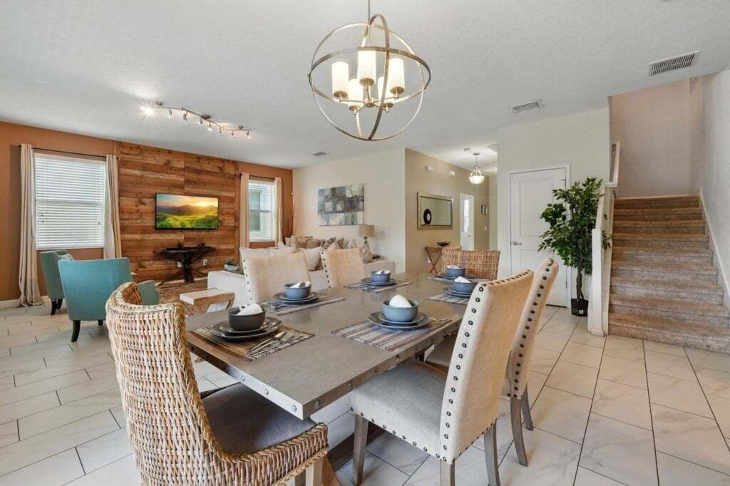 Comedor con una mesa de madera dispuesta para seis personas, rodeado de sillas de mimbre.
