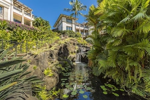 Ein Hotel mit Wasserspiel, üppiger Bepflanzung und blauem Himmel.