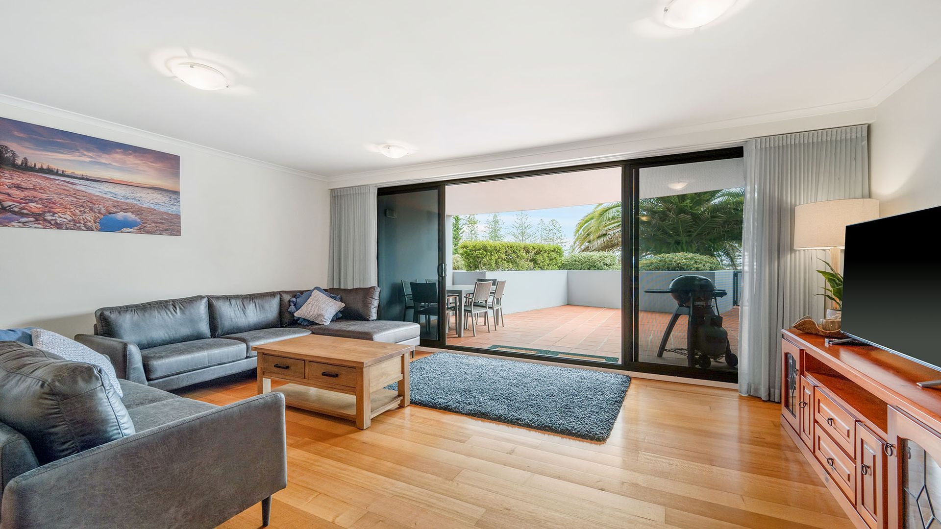 A modern living room with a leather sofa, a coffee table, and a flat-screen TV.