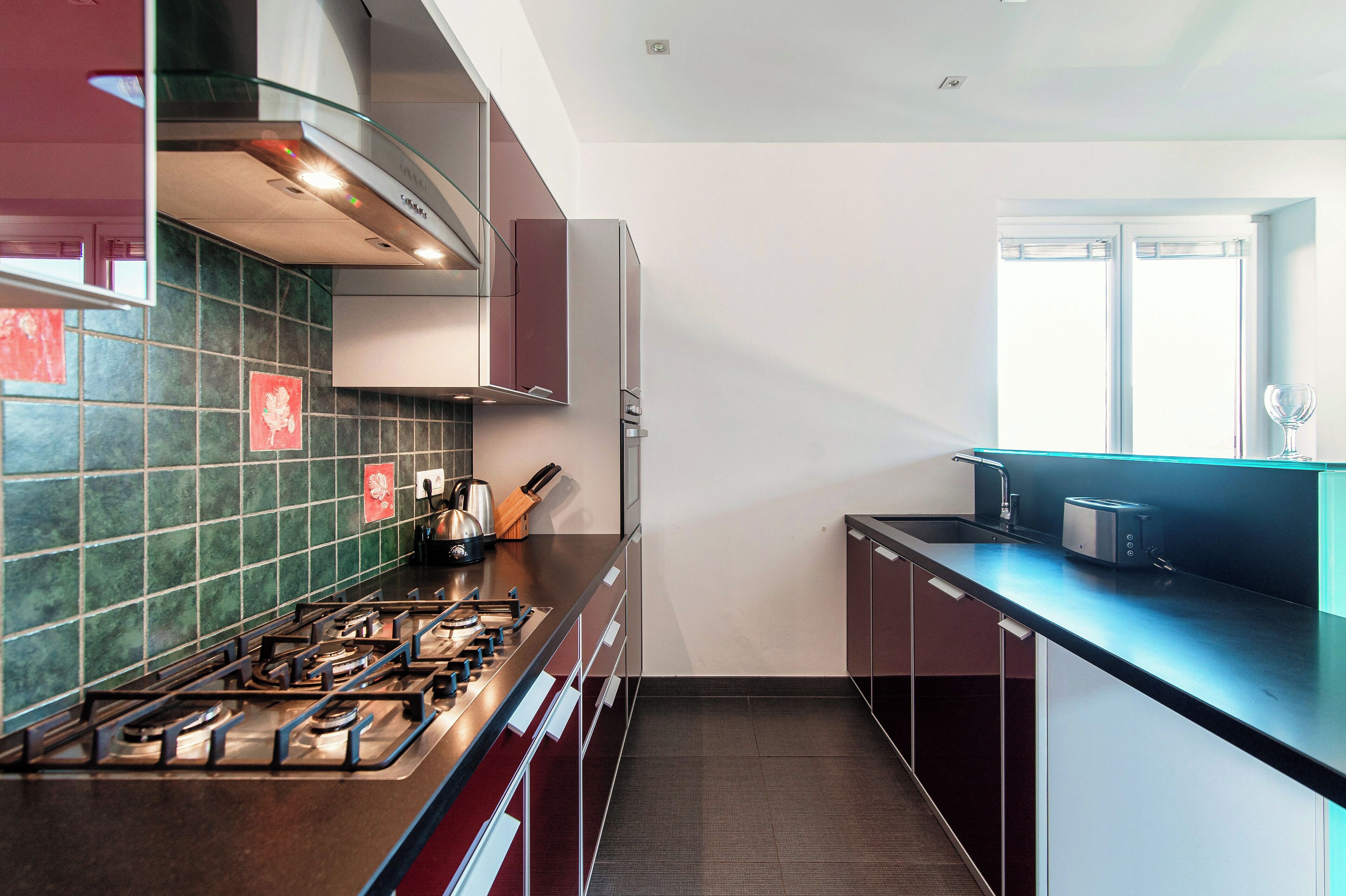 A modern kitchen with a gas stove, stainless steel appliances, and a window providing natural light.