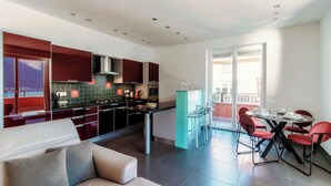 Una cucina moderna con mobili scuri, un'isola centrale e un'area pranzo con sedie rosse.