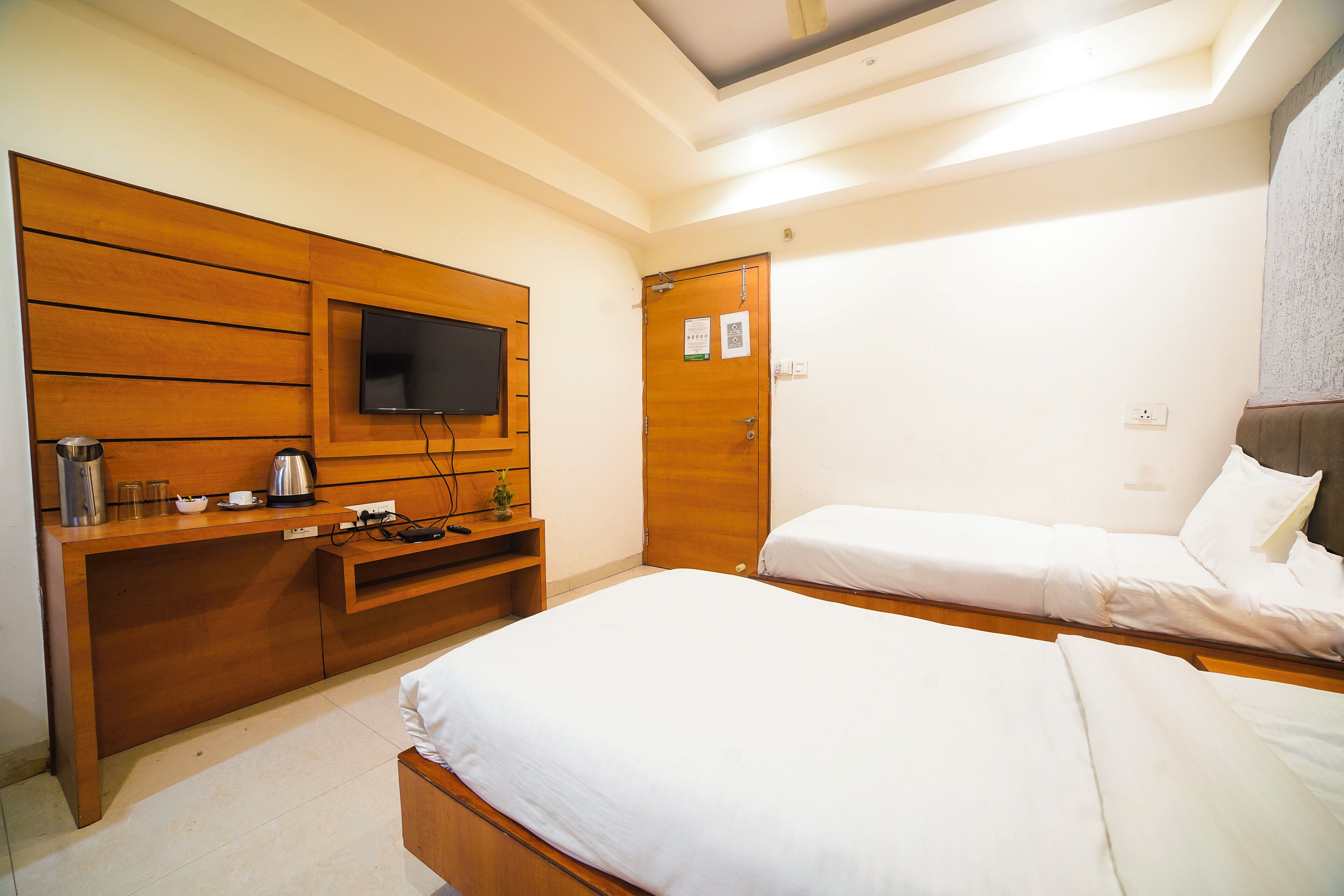 Ein Hotelzimmer mit einem Holztisch, einem Flachbildfernseher, einem Bett und einer Tür mit einem Hinweis.
