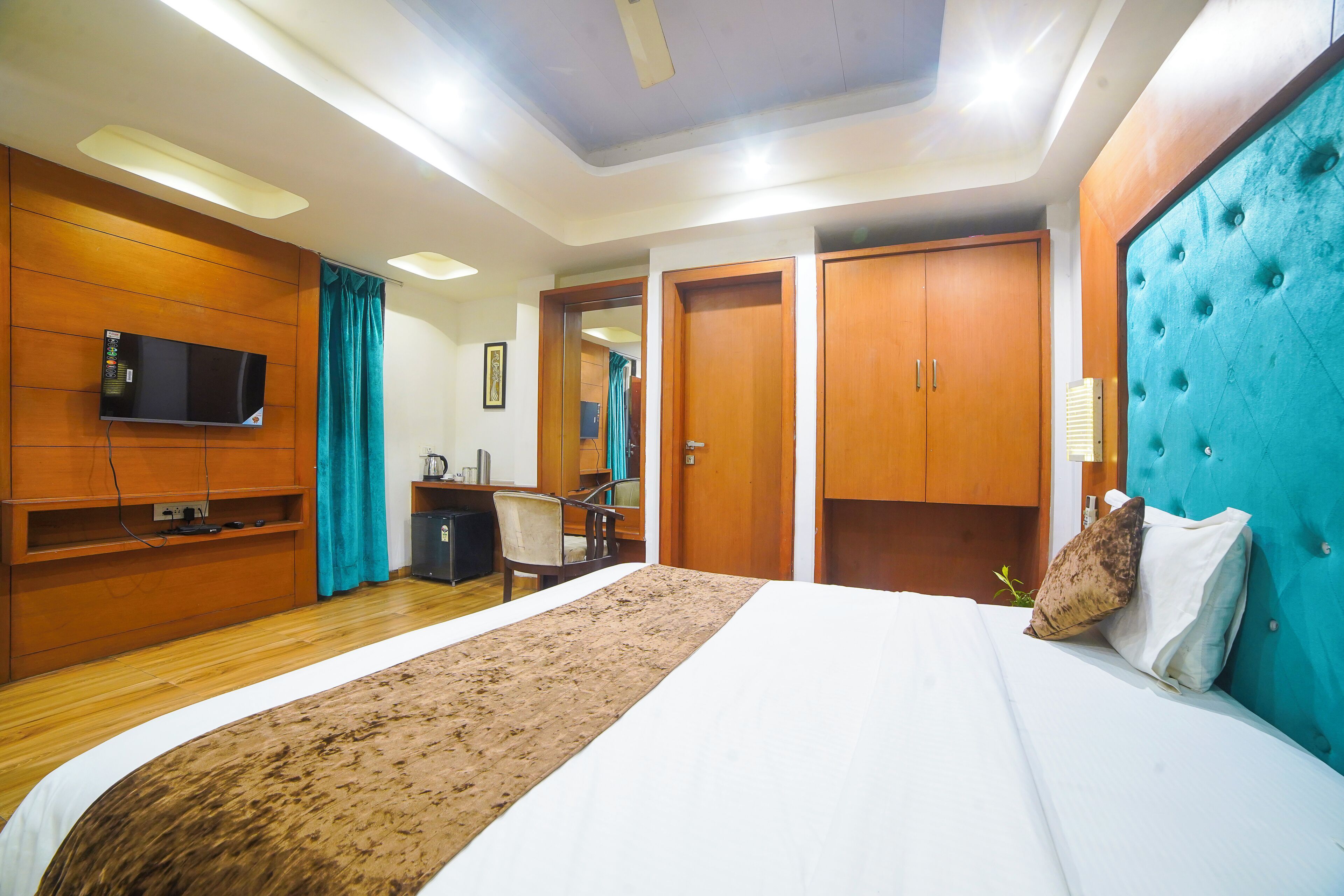 Ein Hotelzimmer mit einem großen Bett, einem Holzschrank, einem Fernseher und einem durchgegangenen Tür angedeuteten Badezimmer.