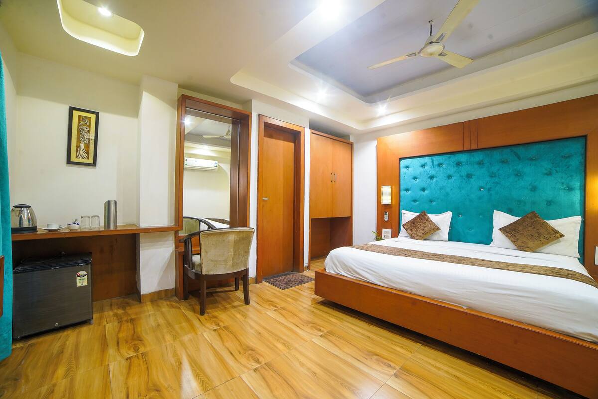 A hotel room with a bed, desk, chair, and a ceiling fan.