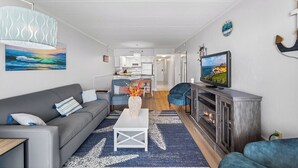 A modern living room with a grey sofa, a white coffee table, and a TV on a wooden cabinet. - Marigot Beach 403 2bedroom Oceanfront (Ocean City)
