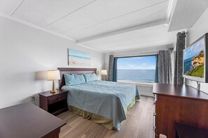 A bedroom with a bed, bedside tables, a TV, a window with a view of the sea, and a painting on the wall. - Marigot Beach 403 2bedroom Oceanfront (Ocean City)