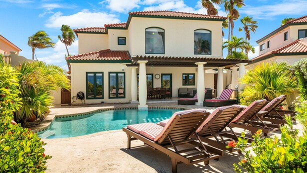 A two-story house with a swimming pool, lounge chairs, and palm trees. - Mesa Vista 15 Tierra del Sol (Noord)