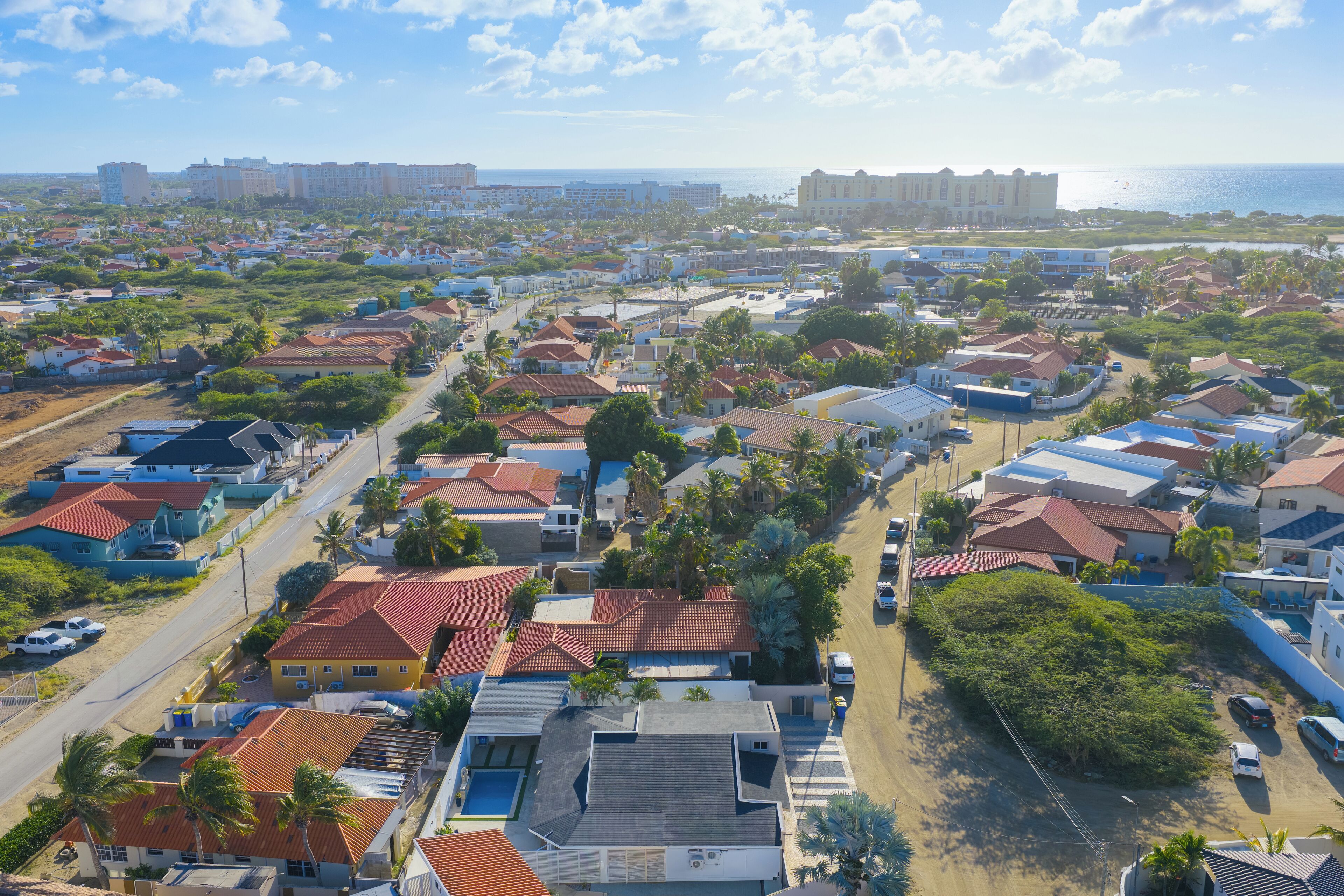 Un barrio residencial con casas, caminos y una playa al fondo.